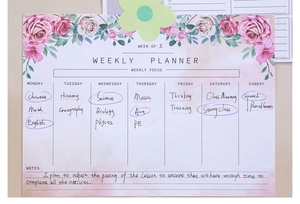 Weekly planner pad detail with pink floral borders and seven-day scheduling sections