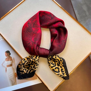 Detail of elegant silk square scarf featuring red floral and leopard print patterns