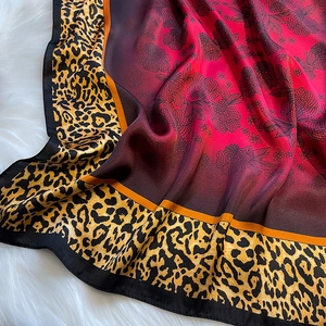 Close-up of smooth silk-like scarf with leopard print edge and red gradient floral pattern