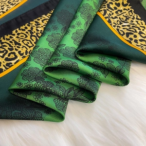 Close-up of leopard print and floral silk scarf with elegant green gradient texture