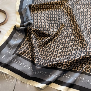 Dettaglio di un foulard di seta con monogramma lettera D e consistenza satinata liscia