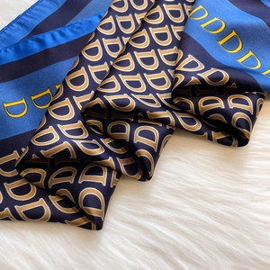 Foulard di seta blu e nero con motivo a lettere dorate su sfondo di peluche bianco