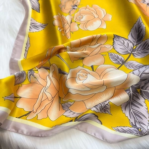 Detail of yellow silk scarf featuring realistic orange rose prints and fine hemmed edges