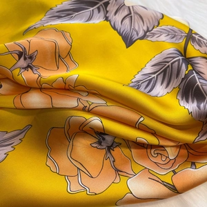 Macro shot of silk scarf fabric showing elegant yellow rose patterns and smooth texture