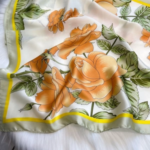 Close-up of yellow rose print silk scarf with fine rolled edges on faux fur background