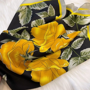 Close-up of yellow rose floral pattern on a black silk-feel square scarf detail