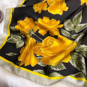 Close-up of elegant black silk square scarf with yellow roses on white faux fur