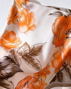 Close-up of orange rose print on silk scarf showing elegant drape and glossy fabric