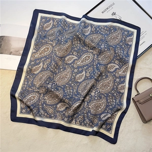 Macro detail of navy blue paisley silk scarf with vintage floral patterns and contrast borders