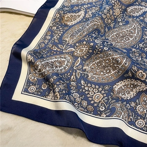 Detail of silk scarf showing paisley pattern on navy blue fabric with sleek texture