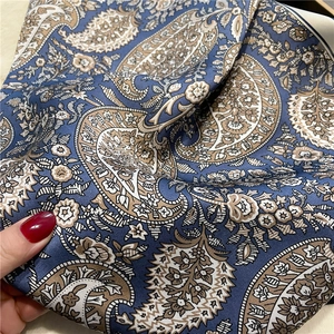 Macro detail of silk-like paisley scarf fabric with elegant navy and beige vintage patterns