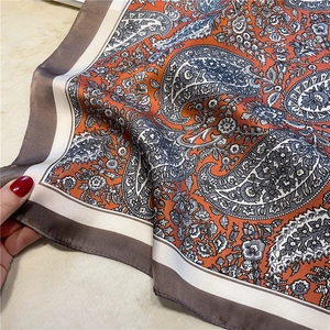 Detailed macro view of paisley pattern silk scarf with orange and grey-blue print