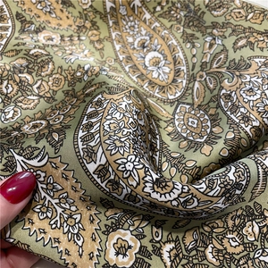 Macro detail of paisley pattern silk scarf with olive green and ivory floral textures