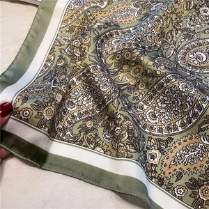 Detail of vintage paisley silk scarf in olive green and beige with fine rolled edges