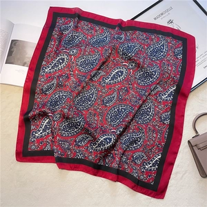 Detail of red and black paisley silk square scarf shown with soft folds on a plush background