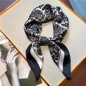 Detail of vintage floral paisley silk scarf tied as a necktie in a gold display tray