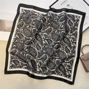 Close-up of vintage black and white paisley silk square scarf on a beige velvet surface