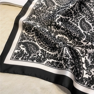 Detail of vintage black and white paisley silk scarf with glossy texture on soft plush