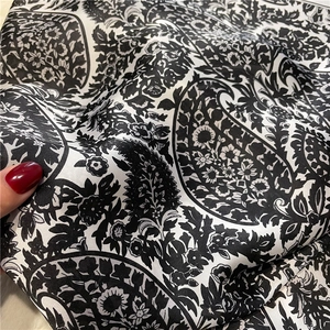 Detail of silk satin scarf featuring classic black and white paisley floral patterns