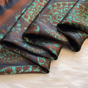 Macro detail of silk scarf showing vintage paisley floral patterns in brown and teal