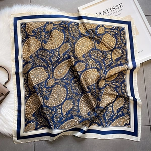 Macro detail of silk scarf featuring classic paisley patterns and elegant navy borders