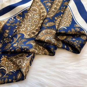 Detailed macro view of vintage paisley silk scarf with elegant gold and navy patterns