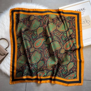 Close-up of vintage paisley pattern silk scarf with orange border on a textured background