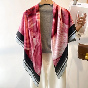 Detail view of pink floral silk scarf draped over shoulders with chic striped borders