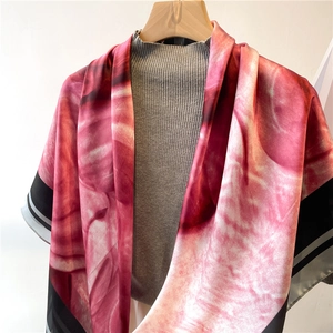 Detail of pink floral silk scarf showing premium draping texture and black contrast border
