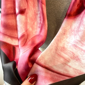 Macro view of light silk scarf with abstract pink and black ink patterns and soft texture