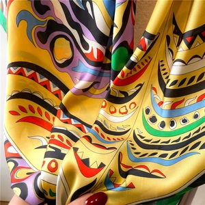 Detailed macro shot of yellow silk scarf showing glossy texture and colorful abstract prints
