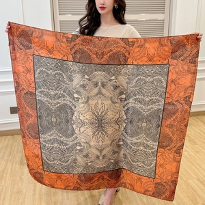 Close-up of a 110cm square silk scarf with vintage phoenix prints in orange and grey