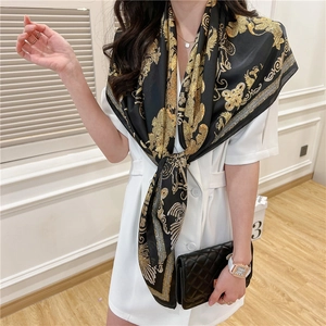 Detail of luxury baroque gold patterns on a black silk scarf draped over a model