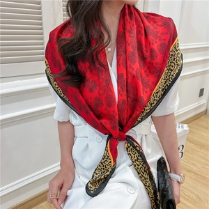 Close-up of red silk scarf with floral print and leopard pattern on white coat