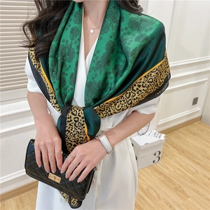 Close-up of vintage silk scarf with green floral patterns and yellow leopard print trim