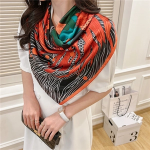 Detail of 110cm square silk scarf featuring abstract orange and green fish scale patterns