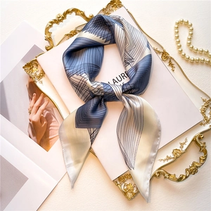 Detail of silk square scarf with geometric blue lines shown in a luxury tray