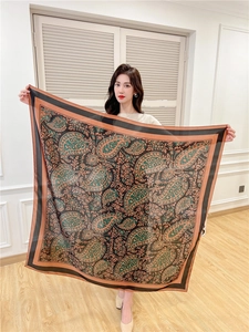 Detail of a large paisley silk-feel scarf in deep green and orange colors