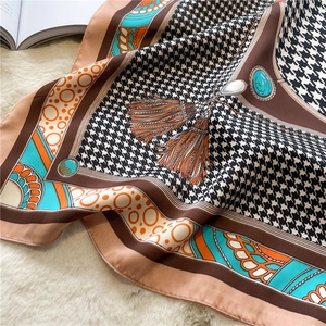 Detail view of houndstooth silk scarf with jewelry patterns on white plush carpet