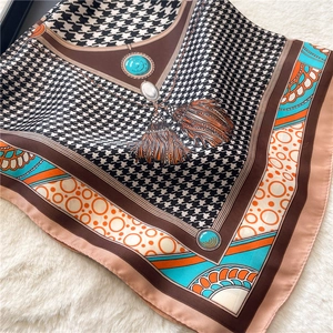 Close-up of houndstooth silk scarf featuring colorful borders and tassel patterns
