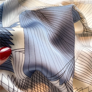 Macro shot of geometric print silk scarf showing soft drape and smooth satin texture