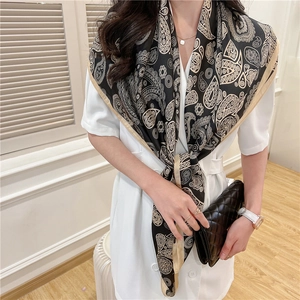 Detail of vintage paisley print scarf in black and gold worn with elegant white dress