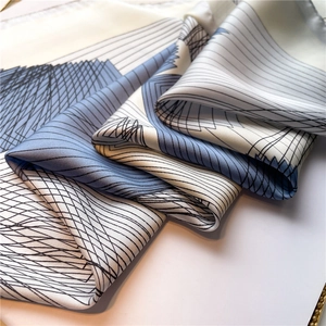 Macro detail of geometric lines on a soft silk square scarf showing premium fabric texture