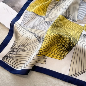Detail of silk square scarf with geometric lines on a soft white plush background