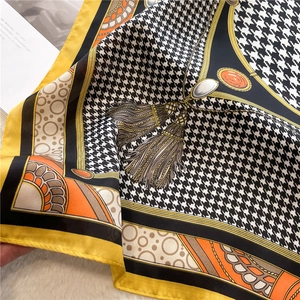 Detail of yellow houndstooth silk scarf showing elegant chain pattern and smooth fabric texture