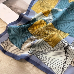 Detail of elegant 70cm geometric silk-like scarf folded on a premium beige faux fur rug
