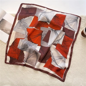 Close-up of geometric pattern silk scarf with orange and brown lines on a white rug