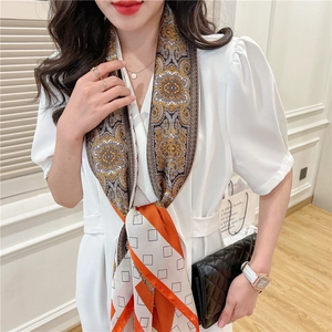 Detail of a retro paisley print silk scarf styled with a white puff sleeve top