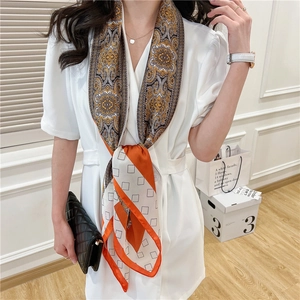 Detail of elegant orange and white paisley floral silk scarf with geometric border