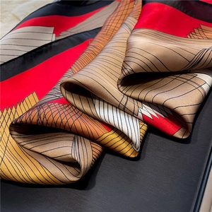 Close-up of silk scarf with geometric red and black patterns showing smooth glossy texture
